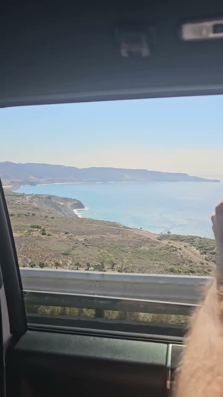 Coastal bay and hills viewed through a vehicle window during the trip